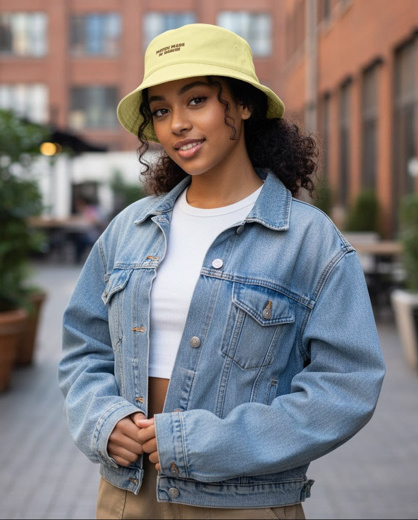 Person wearing a denim jacket and yellow bucket hat outdoors