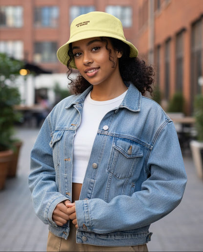 Person wearing a denim jacket and yellow bucket hat outdoors